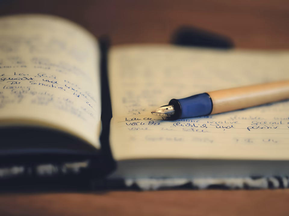 Fountain pen resting on an open handwritten notebook in warm light