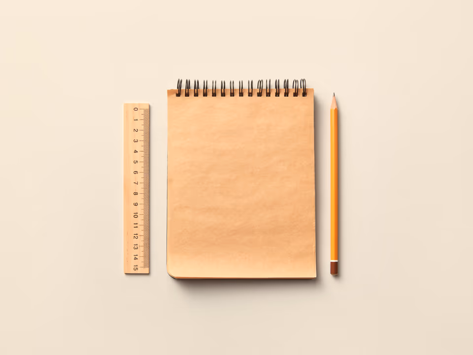 A kraft notepad, wooden ruler and pencil on a pale surface