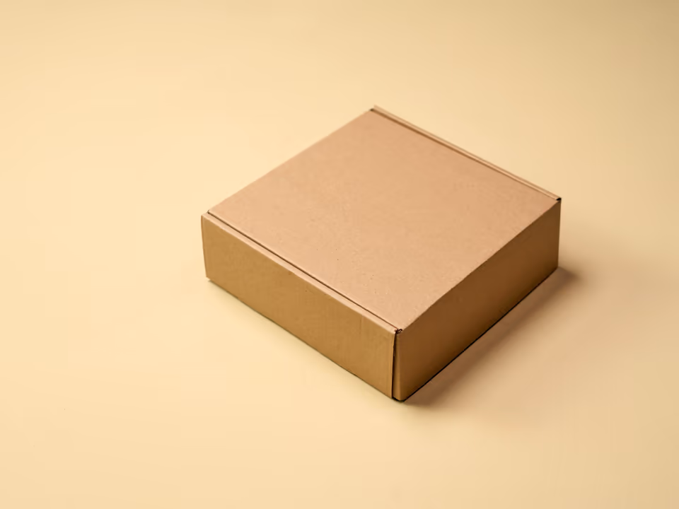 A plain kraft cardboard box on a warm cream table